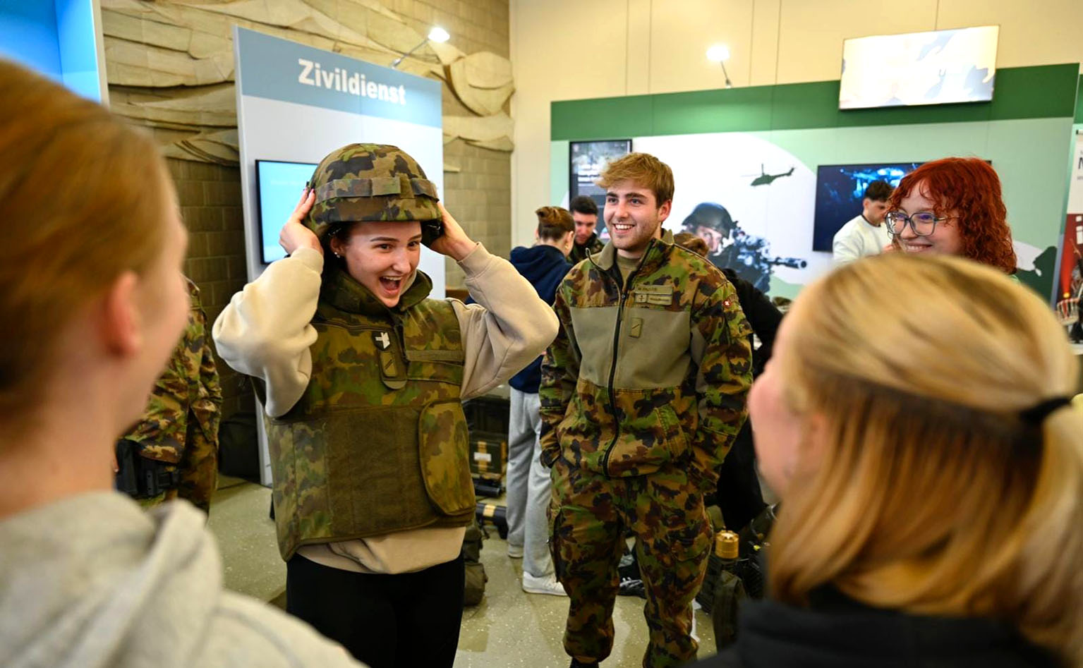 Eine Frau testet einen Helm der Armee und lacht. 