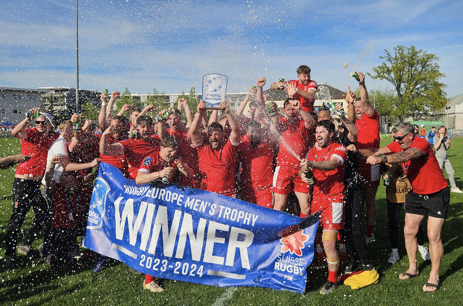 Das Schweizer Rugby-Nationalteam jubelt mit Champagner und einem Banner mit Aufschrift «Winner» auf ...