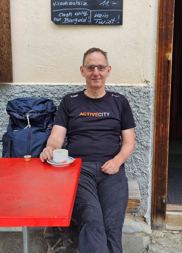 Wanderung Bergün, Val Tuors, Chants, Alp digl Chant: Mario Fehr sitzt während einer Verschnaufpause draussen, auf dem Tisch steht eine Kaffeetasse. 