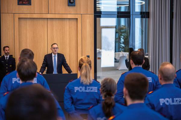 Mario Fehr steht am Rednerpult. Links von ihm befindet sich KAPO-Kommandant Marius Weyermann, mit dem Rücken in Richtung Kamera die Polizistinnen und Polizisten.