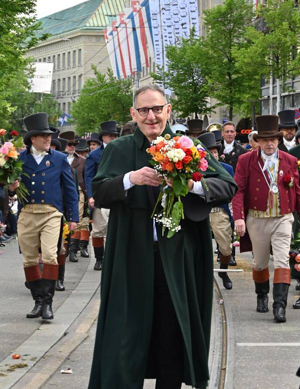 Mario Fehr läuft mit Mitgliedern der Zunft Witikon am Sechseläuten-Umzug 2026 mit. In der Hand hält er einen Blumenstrauss. 