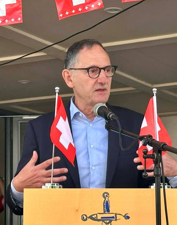 Mario Fehr steht an einem Rednerpult, gestikuliert mit den Händen und spricht. Am Rednerpult sind kleine Schweizer Flaggen befestigt.