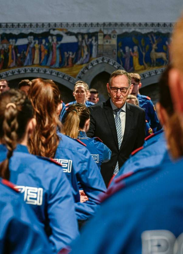 Mario Fehr gratuliert Aspirantinnen der Kantonspolizei, die mit dem Rücken zur Kamera stehen, und lacht.